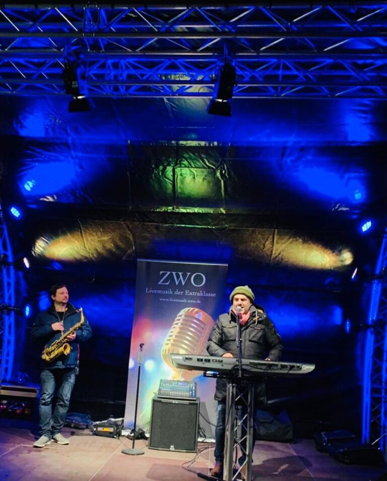 Mitglieder der Liveband ZWO mit Saxophonist und Keyboarder während einer Performance auf einer Bühne.