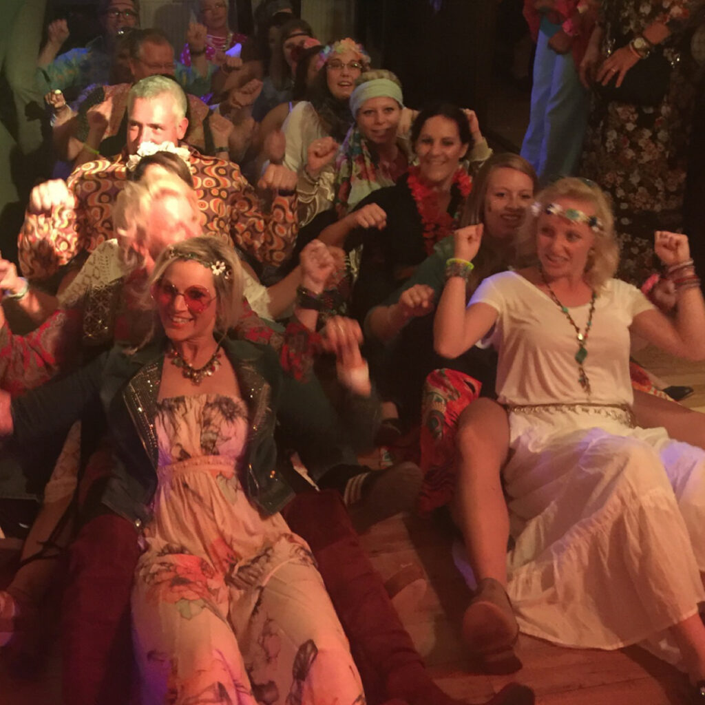 Ausgelassene Gruppe in Kostümen tanzt auf einer Party.